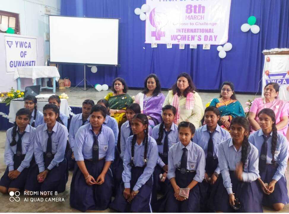 Senior students in uniform seated with their teachers on stage at an International Women's Day event