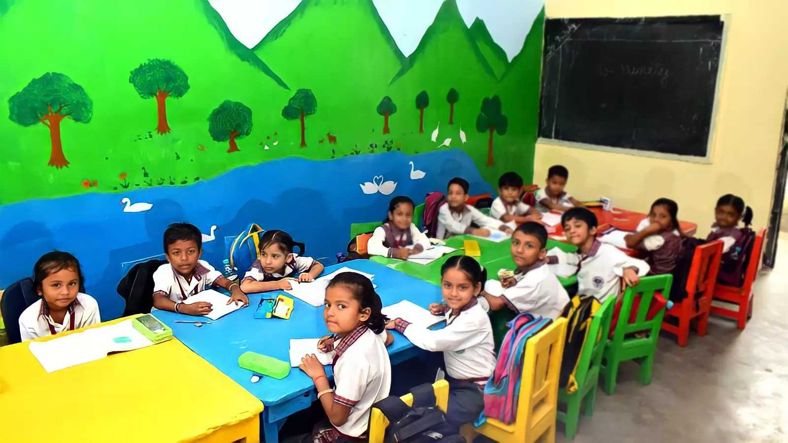 Young students in school uniform at colourful tables in a classroom painted with hills, trees and a river
